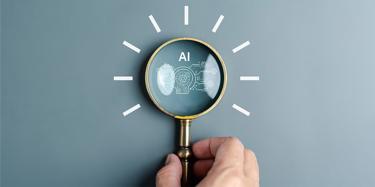 A magnifying glass looking at a graphic representing AI ambitions, which an AI readiness assessment can guide