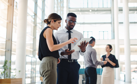 Man and Woman discussing plans for business process in office on tablet