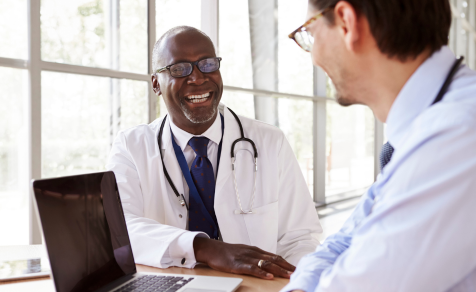 Healthcare professionals smiling and talking in front of computer