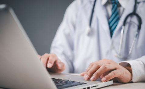 healthcare professional typing on laptop